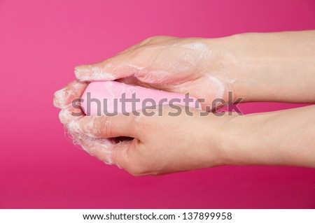 Female hands, soap on a pink background