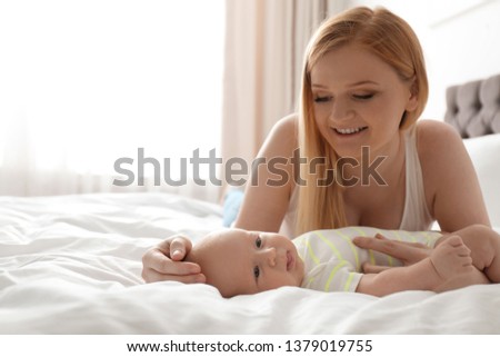 Mother with her little baby on bed at home