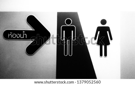 The signpost to the toilet consists of ... black arrow symbol, written in Thai which is translated into English ... toilet and symbolizes women and men...black and white picture.