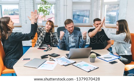 Front view shot of five happy business people celebrating success giving high five to each other, looking excited after signing profitable contract. Teamwork concept.