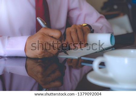 Business man  writing and signing  checkbook, work on laptop computer with white cup of coffee on the desk. Cheque payment concept.