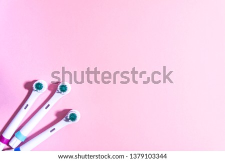 Electrical toothbrushes on a soft light pink background.