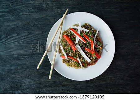 Asian cuisine. Cellophane noodles decorated with vegetables, greens. Funchoza. Proper nutrition. Healthy food. View from above. Dark wooden background.