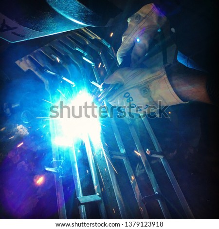 Closeup of a welder welding a piece of metal art creating a beautiful blue light