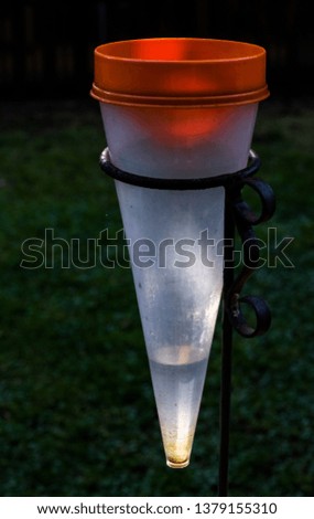 A rain gauge with a small amount of water in it highlighted by the early morning sun isolated on a dark background image with copy space in portrait format