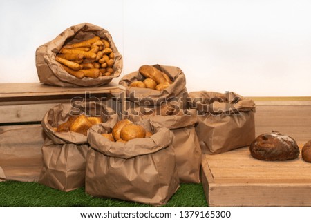 Selection of Fresh baked bread baskets and paper bags with bread roasted in the oven, croissants, baguettes, whole integral bread and pastry, rustic wood background