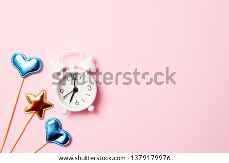 Retro alarm clock with party decoration on pink background. Copy space