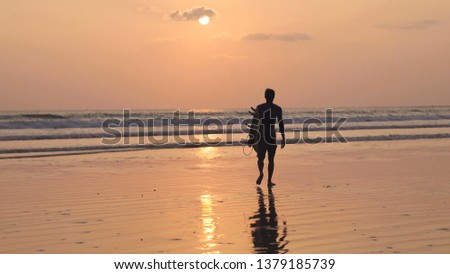 A man walk with surfboard at sand beach sunset time