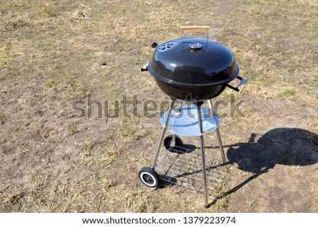 Large closed round grill with a thermometer. Grill on wheels. The process of cooking barbecue. The concept of relaxation and enjoyment of food