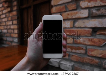 phone with black screen in hand on brick wall background, space for text