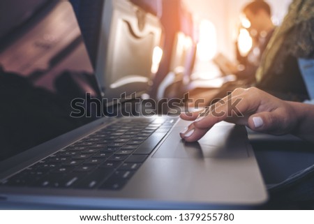 Closeup image of a woman using and touching at laptop computer touchpad while sitting in the cabin