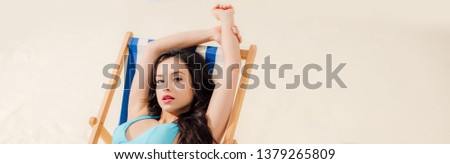 panoramic shot of beautiful girl in bikini relaxing on deck chair on beach with copy space