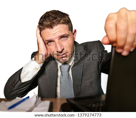 young frustrated and stressed businessman in suit and tie working overwhelmed at office laptop computer desk desperate and worried cause of work stress isolated on white background