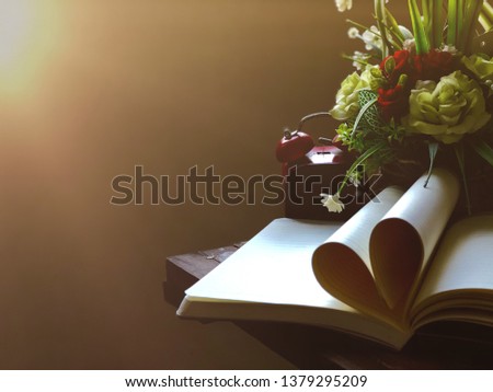 Still life image,Roses Flowers bouquet,Book page rolls,like shaped the heart,and red alarm clock,on old wood planks,with lens flare.Dark tone,dimly light.Memories for Valentine concept.Selective focus