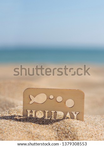 Card announcing the summer holidays in the sand on the beach. Word stamped on wood.
