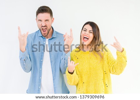 Young beautiful couple togheter over isolated background shouting with crazy expression doing rock symbol with hands up. Music star. Heavy concept.