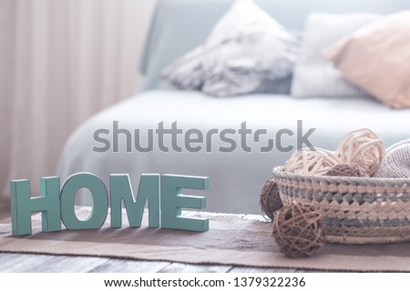 Home cozy interior with wooden inscription home, on the background of the sofa with pillows
