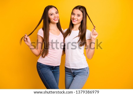 Close up photo two people beautiful she her ladies models long straight hairdo playing curls romantic mood toothy smile hugging stand close wear white pink casual t-shirts isolated yellow background