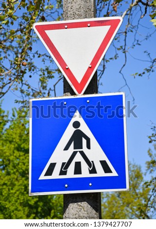 Yield and pedestrian traffic signs on a pole