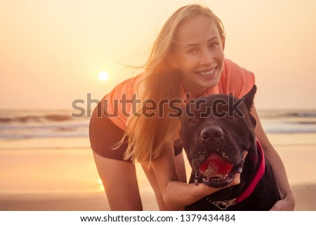 girl taking pictures photos of yourself on phone camera with their big dog Cane Corso black on indian ocean sea beach goa at sunset