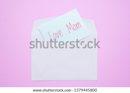Love mom word on paper card with letter envelope on pink background. Mother's day concept.