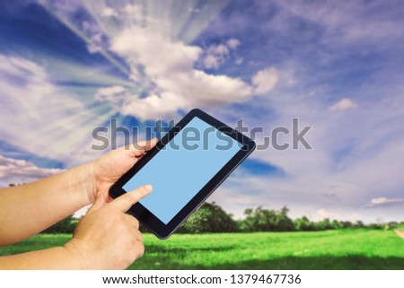 Hand hold a tablet with nature background.
