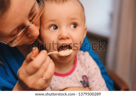 mother feeds a small child with a spoon