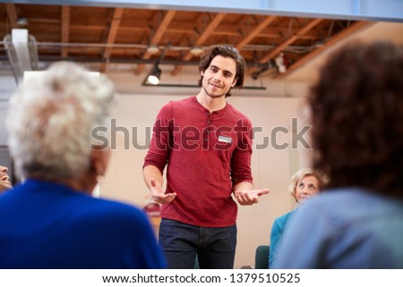Man Standing To Address Self Help Therapy Group Meeting In Community Center Royalty-Free Stock Photo #1379510525