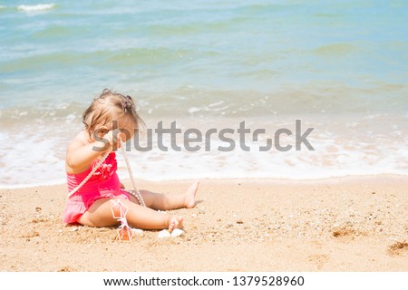 girl in a bathing suit with white beads is surprised, rejoices, shouts, raises her hands. children's fashion concept
