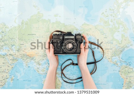 Cropped view of woman holding film camera on world map