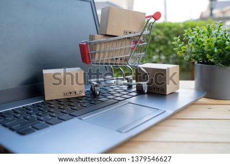 Boxes in a trolley on a laptop keyboard. Ideas about online shopping, online shopping is a form a seller over the internet. - Image