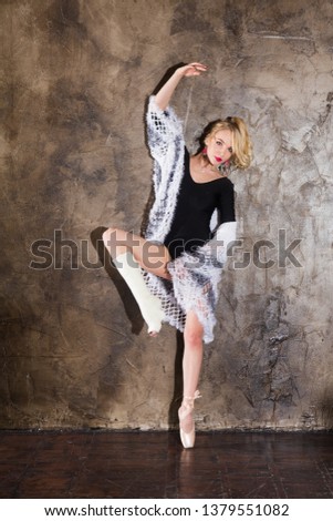 Young woman ballerina with crutch and broken leg dances against the background of a wall