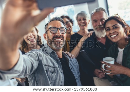 Group of happy people taking selfie in office. Start up entrepreneur at office taking selfie with his team.