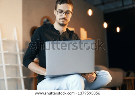 Young man sitting with computer. Freelancer in glasses working with laptop, project manager.