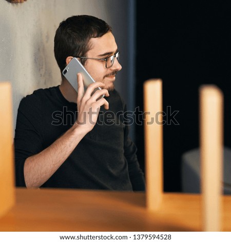 Young man working with phone and computer, receiving phone call, talking with partners 