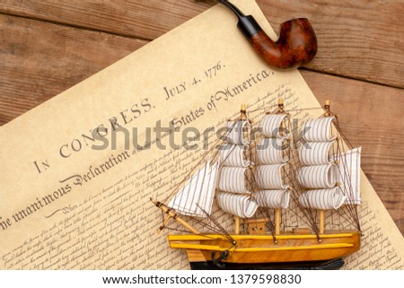 Ship made of wood and fabric handmade on the background of an excerpt from a copy of the document of 1776 on the signing of the independence of America