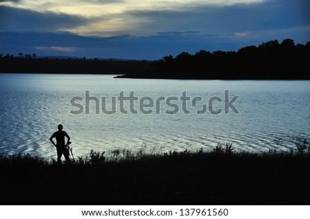 Photographer and tripod in twilight landscape