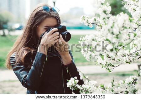 beautiful young woman taking pictures of flowering trees