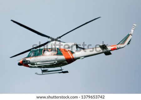 White-orange helicopter is flying in blue sky