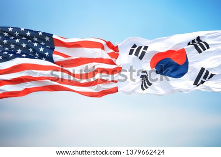 Flags of the USA and South Korea against the background of the blue sky Royalty-Free Stock Photo #1379662424