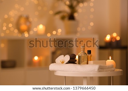 Spa supplies, burning candle and flower on table in beauty salon, space for text Royalty-Free Stock Photo #1379666450