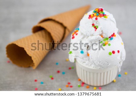 plate of vanilla ice cream scoop swith sprinkles and waffle cones.