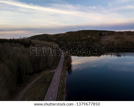 Areial view of road between forest an lake 