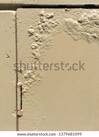 Beige metal plate with paint bubbles and a hinge.