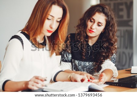 Girls are sitting at the table.Beautiful girls work in the office. Women with a computer