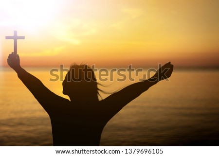 Man standing holding christian cross for worshipping God at sunset background. christian silhouette concept.
    
    - Image