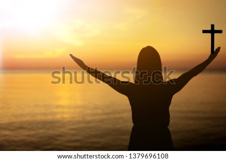 Man standing holding christian cross for worshipping God at sunset background. christian silhouette concept.
    
    - Image
