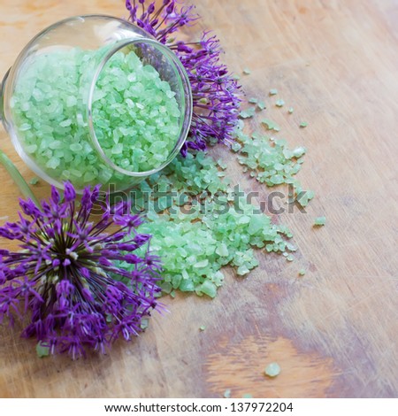 Sea salt in bowl with flowers on  wooden background. Selective focus.