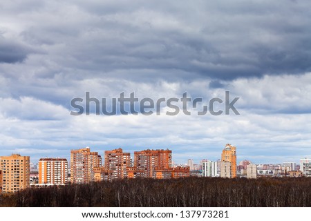 low grey rainy clouds under urban houses in spring