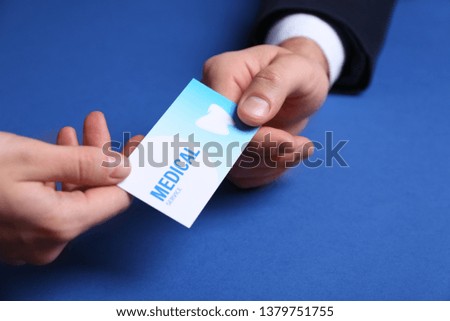 Man giving business card to woman on color background, closeup. Dental medical service